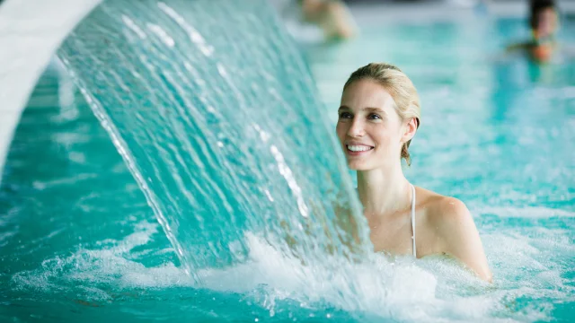 Woman enjoying hydrotherapy and water stream in spa pool